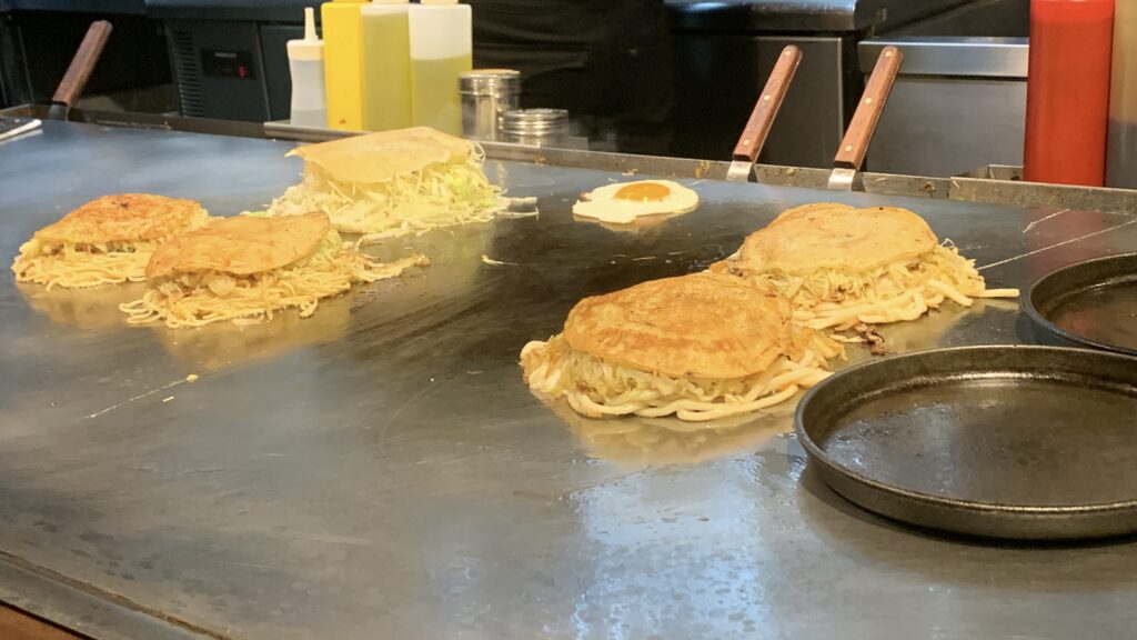 en 鉄板でお好み焼きを焼く様子 山本