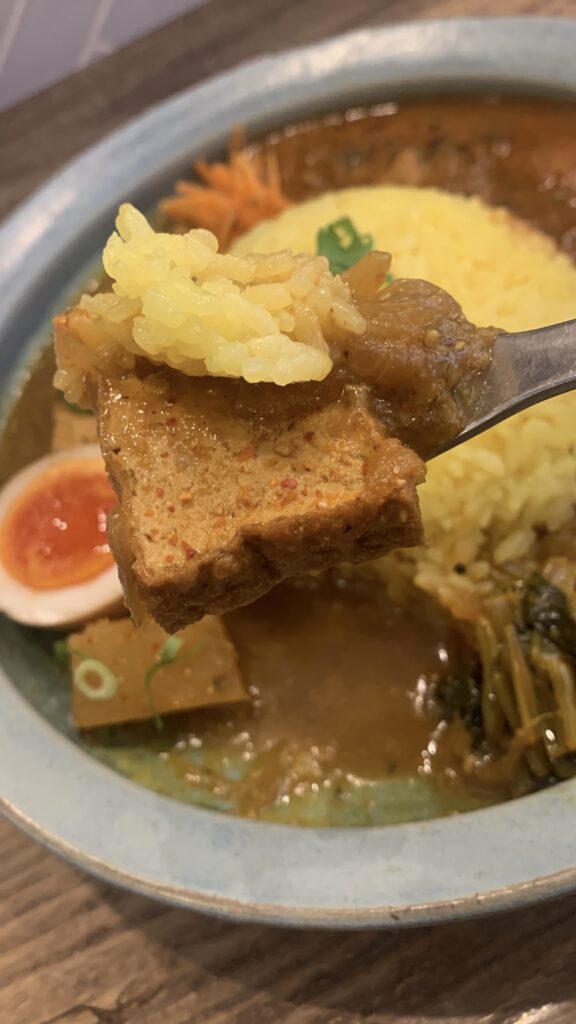 みとむや 5周年 週替わりカレー祭5週目 厚揚げと根菜の塩麹カレー スプーンですくった厚揚げとライス