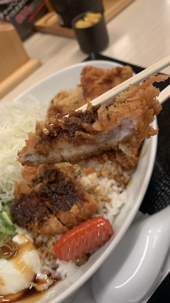 かつや 欲張り飯のロースカツを箸で持ち上げたところ