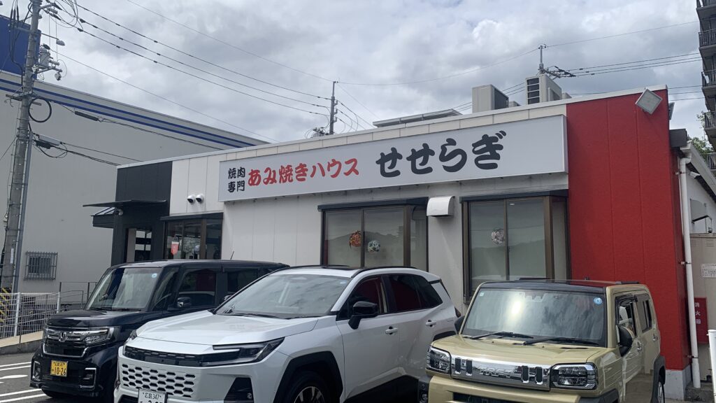 あみ焼きハウス せせらぎ 外観 白い建物と赤い壁 駐車場の車