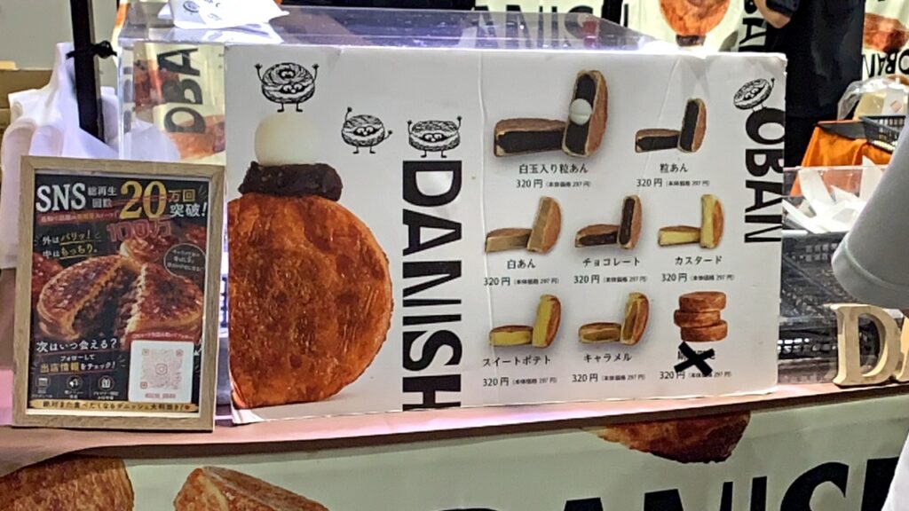 「DANISH OBAN」のメニュー表（7種類・各320円）と、SNS総再生回数20万回突破の掲示