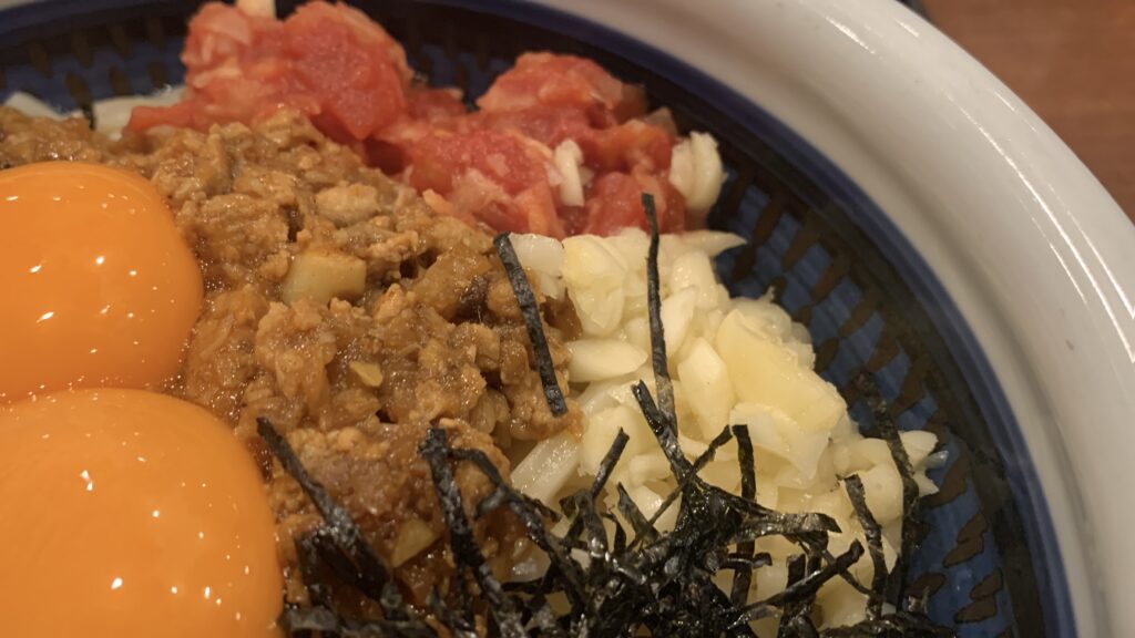 丸亀製麺 肉辛まぜうどん ガリトマトとニンニク 卵黄のアップ