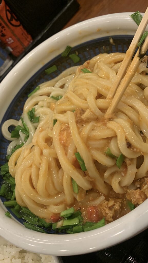 丸亀製麺 肉辛まぜうどん 混ぜたうどんを箸でもち上げたところ